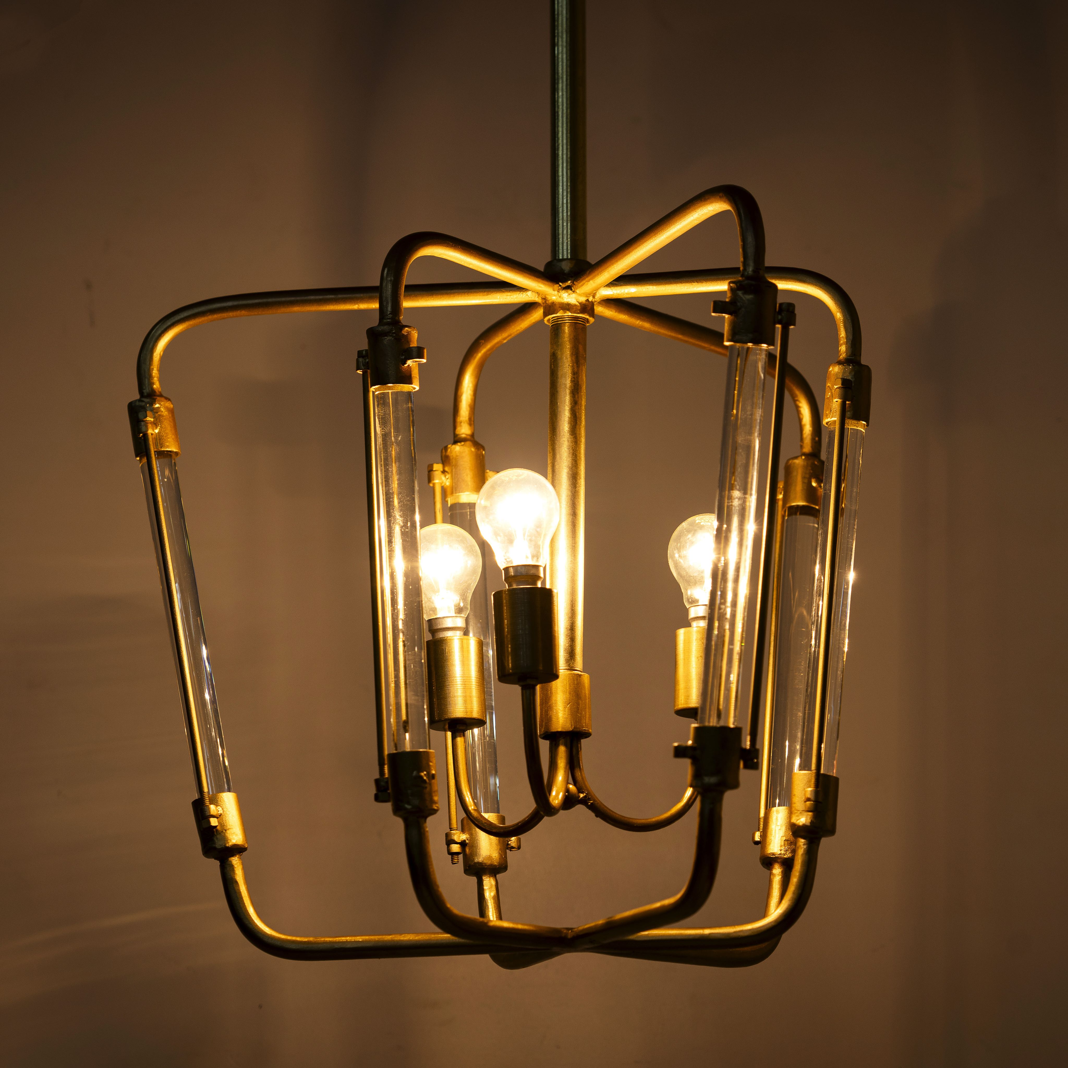 Lighted version of a large round pendant lamp in antique brass with test tube glass – minimalistic style pendant light combining vintage metal lighting and elegant glass accents.