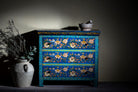 Lifestyle image of a hand-painted cupboard made of reclaimed wood with floral drawer fronts – Divisha model by Om Home & Garden