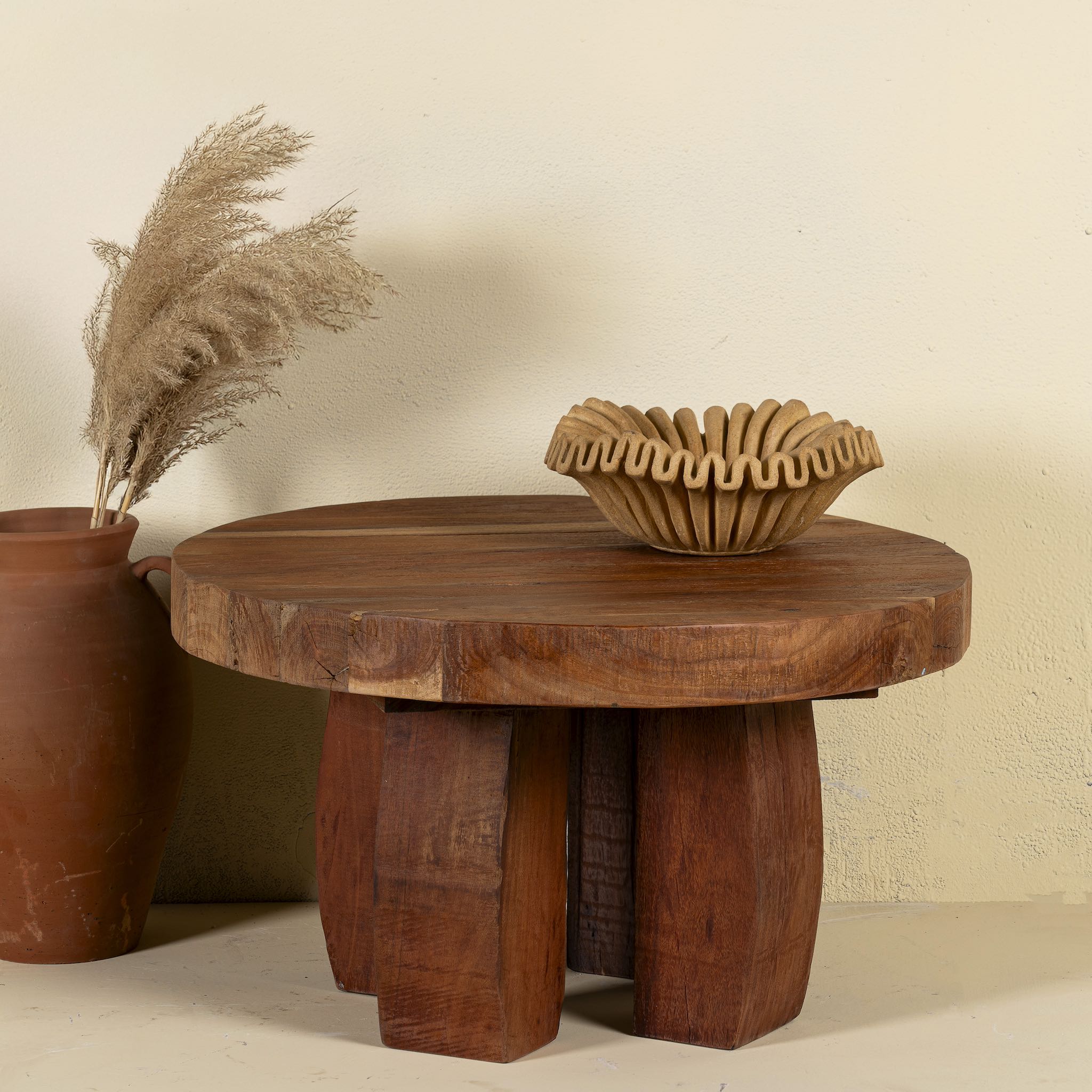 Front view of a wabi-sabi style rustic coffee table made of reclaimed wood in a living room scene in front of a light coloured wall.