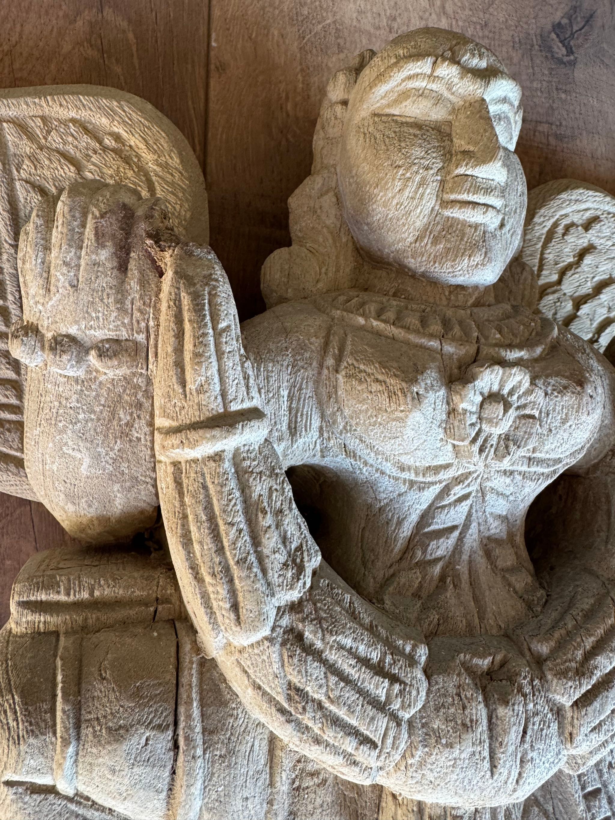 Close up image of a hand-carved Indian deity wall sculpture with wings, made from reclaimed wood with sandblasted finish – spiritual wall decoration, 30x40x5cm.