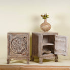 Open door picture of a pair of hand-carved bedside tables made of mango wood, featuring intricate round floral motifs on the doors, crackled vintage finish, and elegant curved legs in a distressed antique design.
