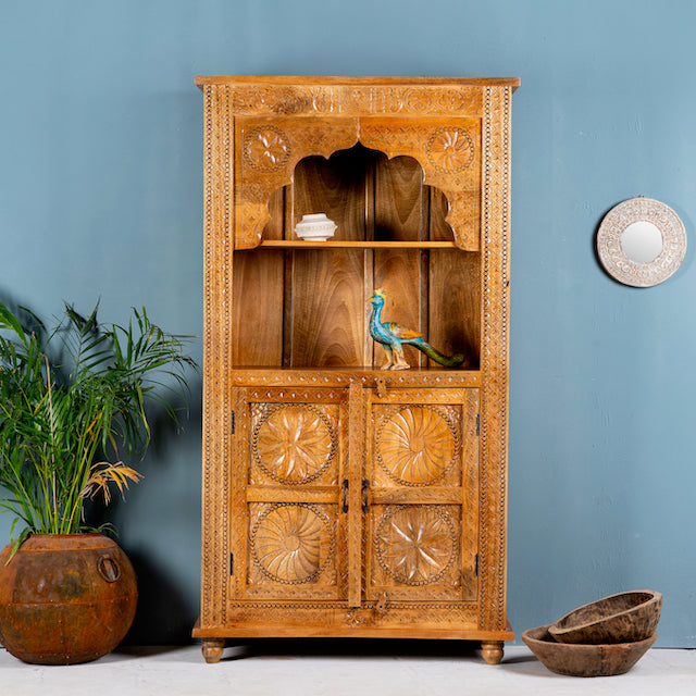Hand-carved mango wood shelf with four compartments and an open shelf, featuring intricate floral patterns, in a bohemian style, with a bird figurine on the upper shelf.