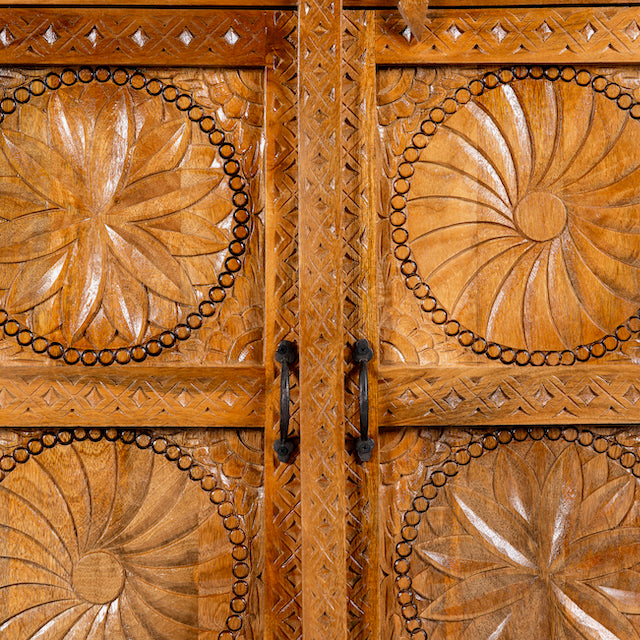 Close up image of a hand-carved mango wood shelf with floral detailing, open shelf, and carved legs – carved wooden furniture in honey finish for rustic and Mediterranean interiors.