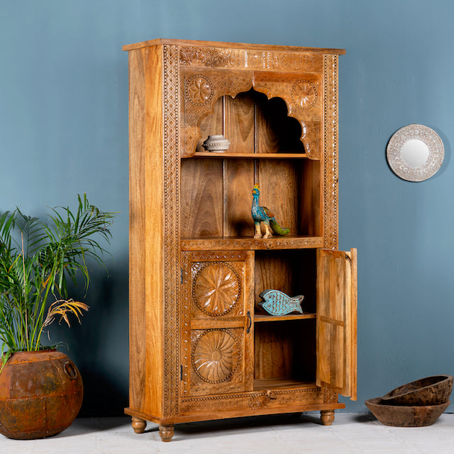 Side angle image with open doors of a hand-carved mango wood shelf with floral detailing, open shelf, and carved legs – carved wooden furniture in honey finish for rustic and Mediterranean interiors.