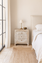 Bedroom with a textured nightstand and lamp near a bed.