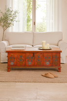 Lifestyle image of a hand-painted teak reclaimed wood chest – sustainable handcrafted furniture serving as a coffee table and artistic storage solution.