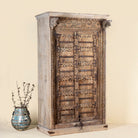 Side angle picture of a unique wardrobe made from a reclaimed old teak wood door, featuring original iron fittings and hand-carved floral details in a rustic vintage finish.