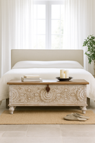 Lifestyle Image of a Hand-carved mango wood chest box with floral motifs, whitewashed finish, and iron handles – vintage home accessory for rustic and elegant interiors.
