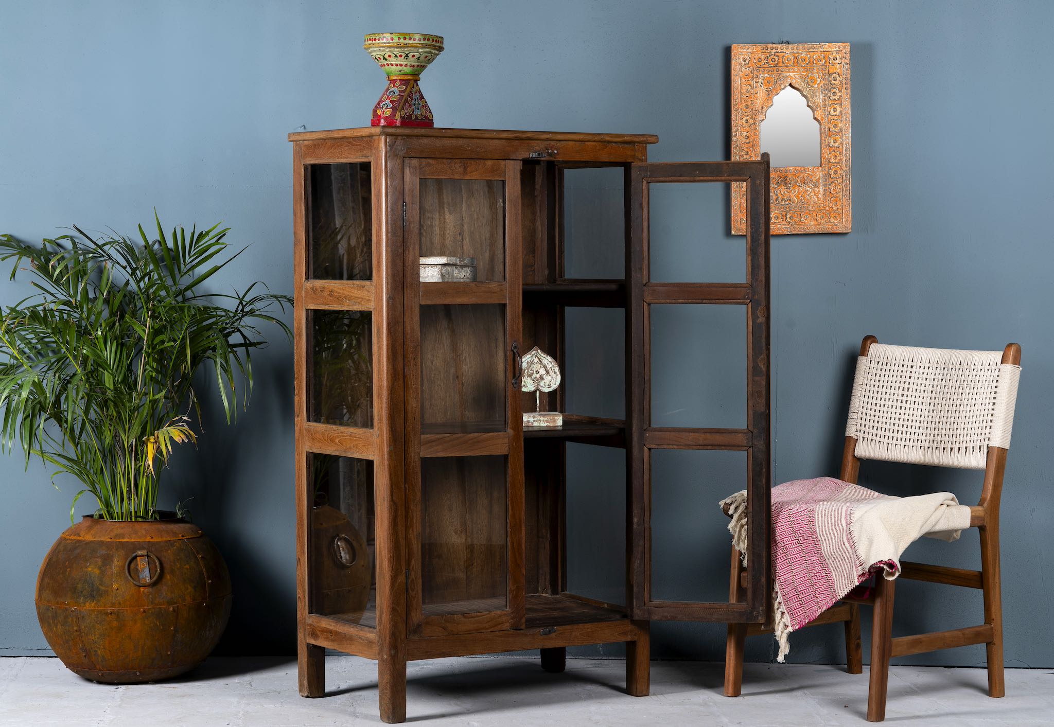 Side angle image with open doors of a compact reclaimed teak wood display cabinet with two glass doors and shelving – sustainable teak wood furniture combining functional design and unique character.