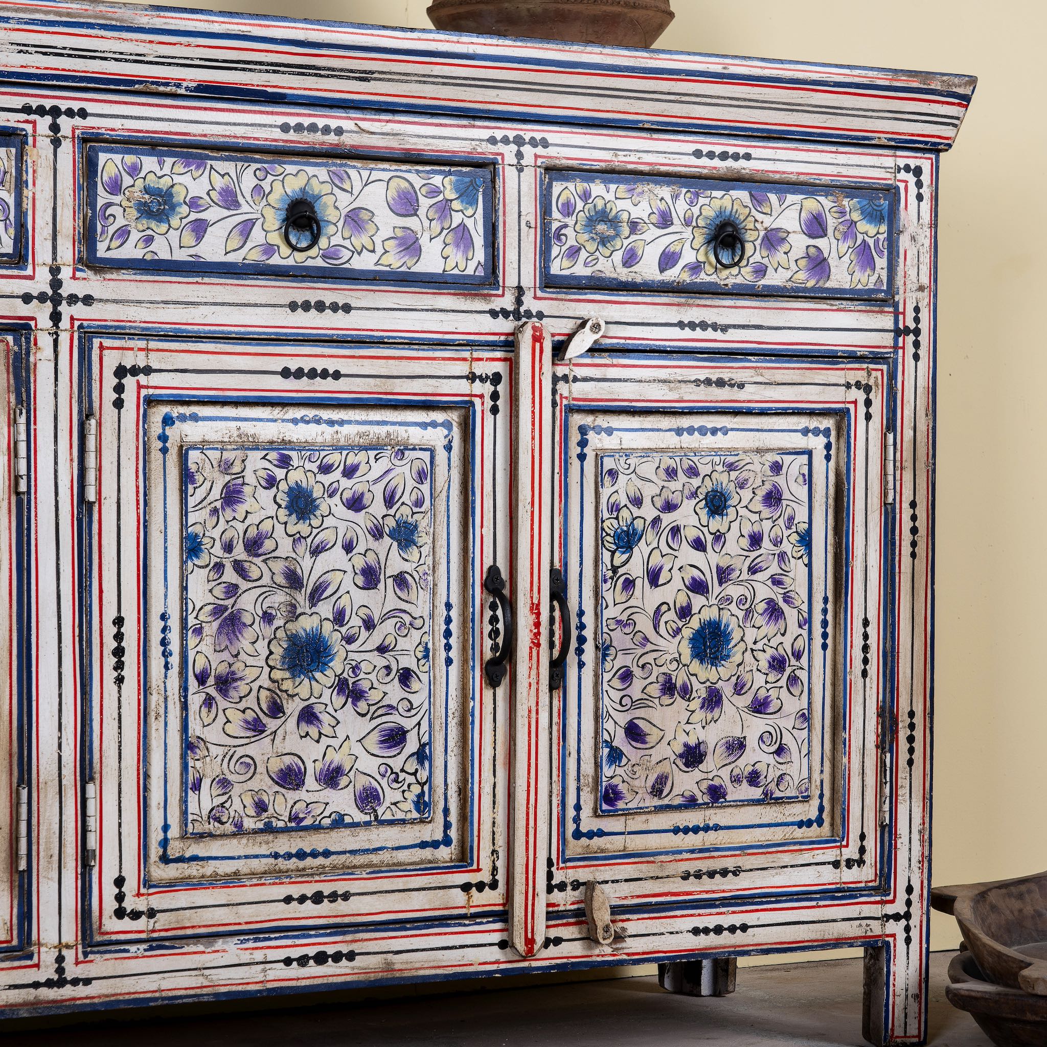 Close up image of a hand painted sideboard in reclaimed wood, an artisanal furniture piece with floral motifs and multicolour finish.