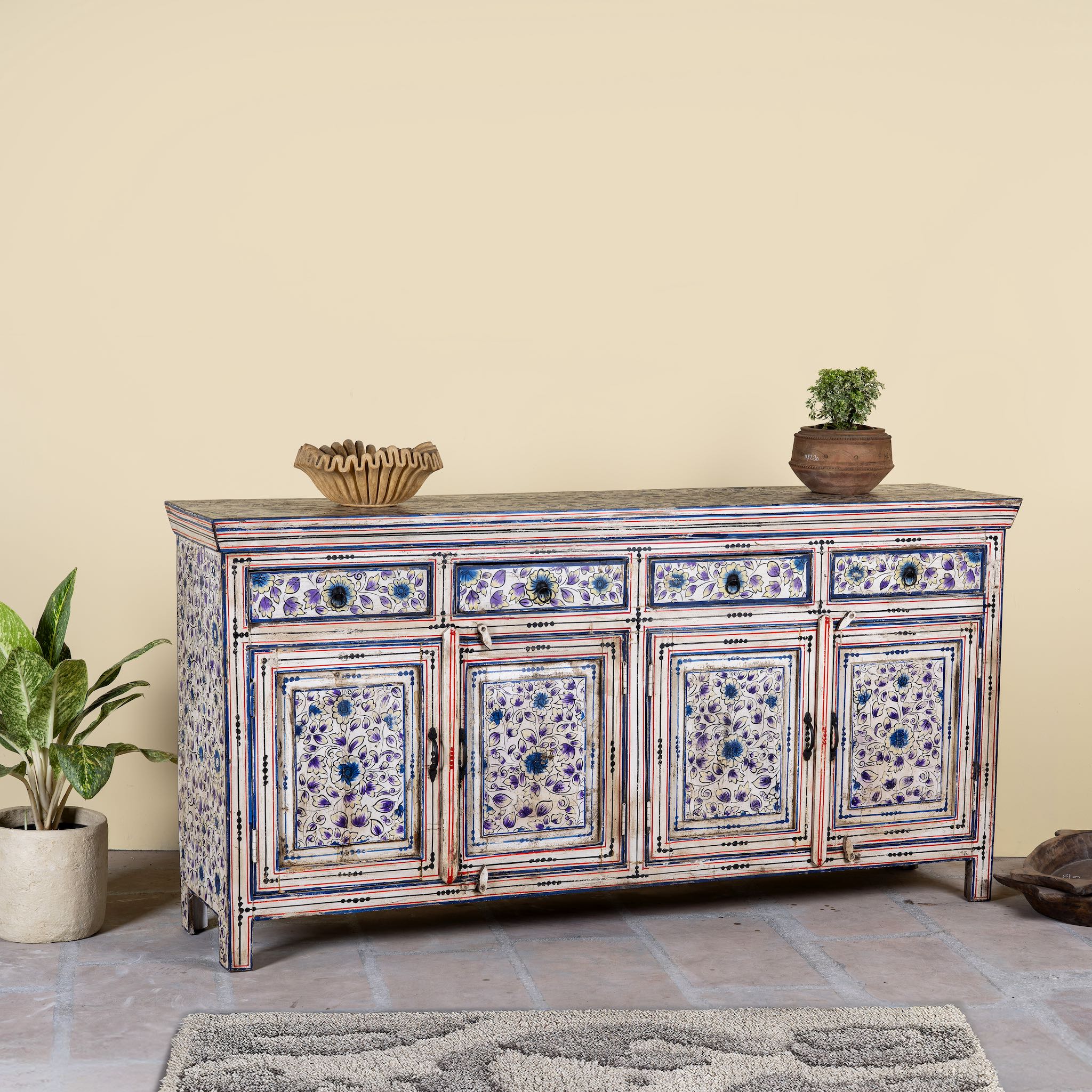 Side angle image of a hand painted sideboard in reclaimed wood, an artisanal furniture piece with floral motifs and multicolour finish.