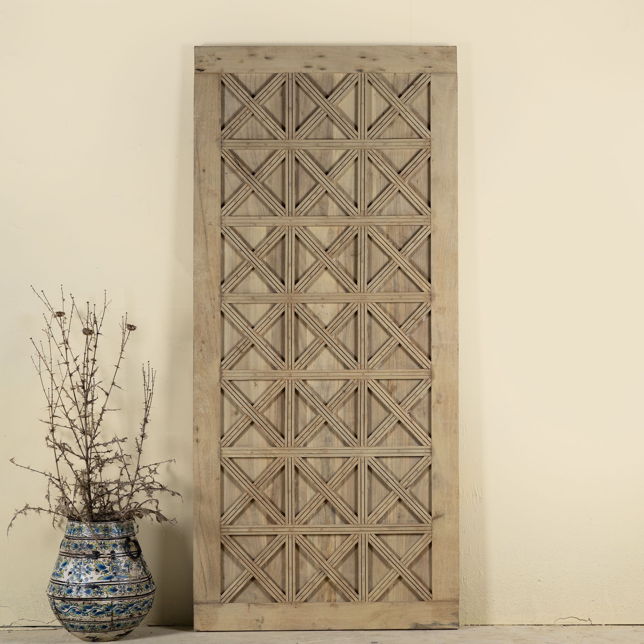 Sliding door panel crafted from reclaimed wood, featuring a bold geometric grid design with layered X-pattern carvings for a modern rustic look.