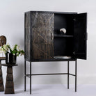 Side angle image with open door of a black wooden cabinet with handcrafted copper inlays and nickel-plated metal base—an artisanal furniture piece with a refined minimalistic style.