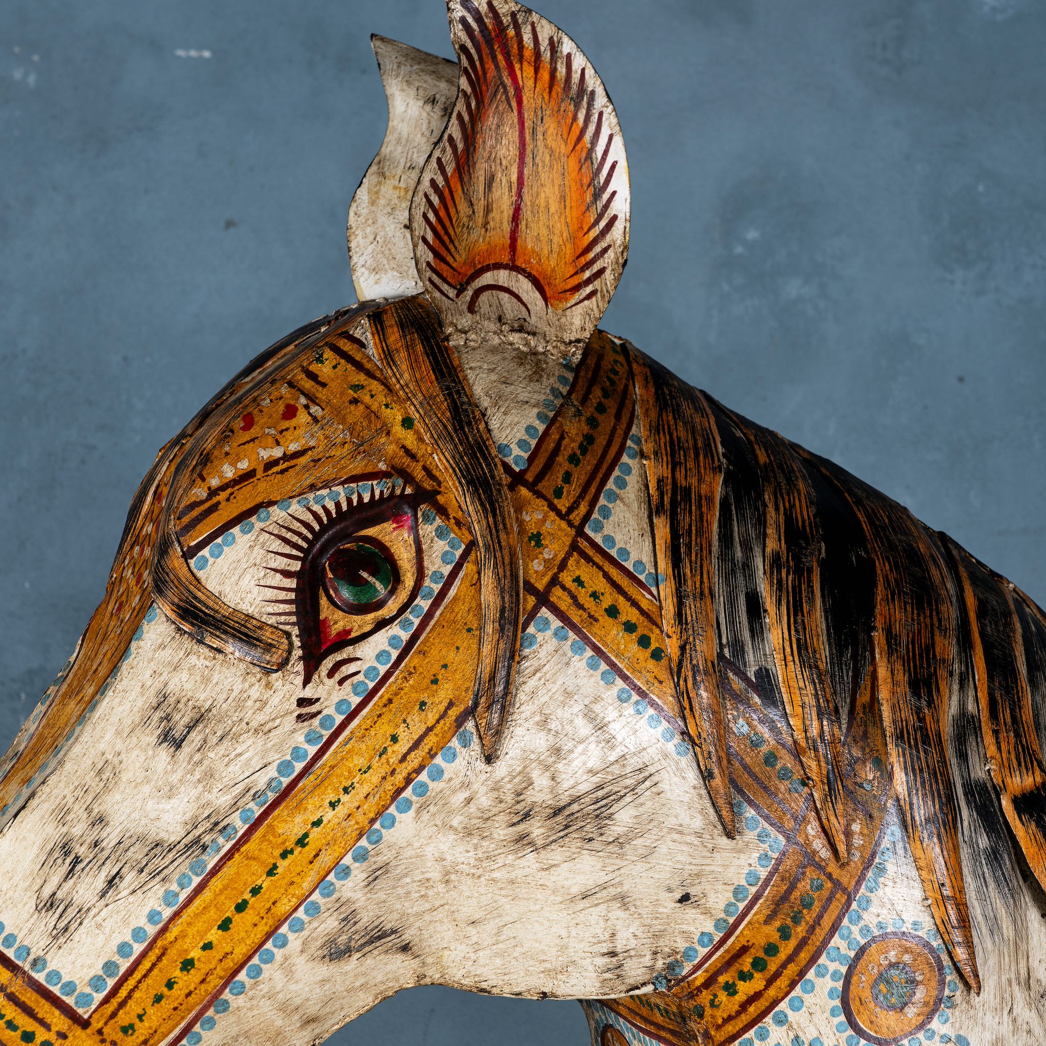Close up of a large hand-painted decorative horse sculpture made of sheet metal in vibrant Rajasthani style, featuring intricate floral and geometric patterns in red, green, and black. Ideal for enhancing entrance areas, restaurant lobbies, hotel receptions, or luxury interior spaces.