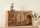 Side angle image of a hand-carved mango wood sideboard with rattan inserts, featuring two cabinet doors with rattan fronts and six drawers, placed against a neutral backdrop with decorative items on top.