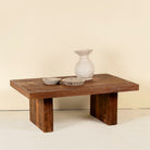 Minimalist coffee table made from reclaimed wood, featuring a solid rectangular top and block legs for a clean, contemporary look with rustic warmth.


