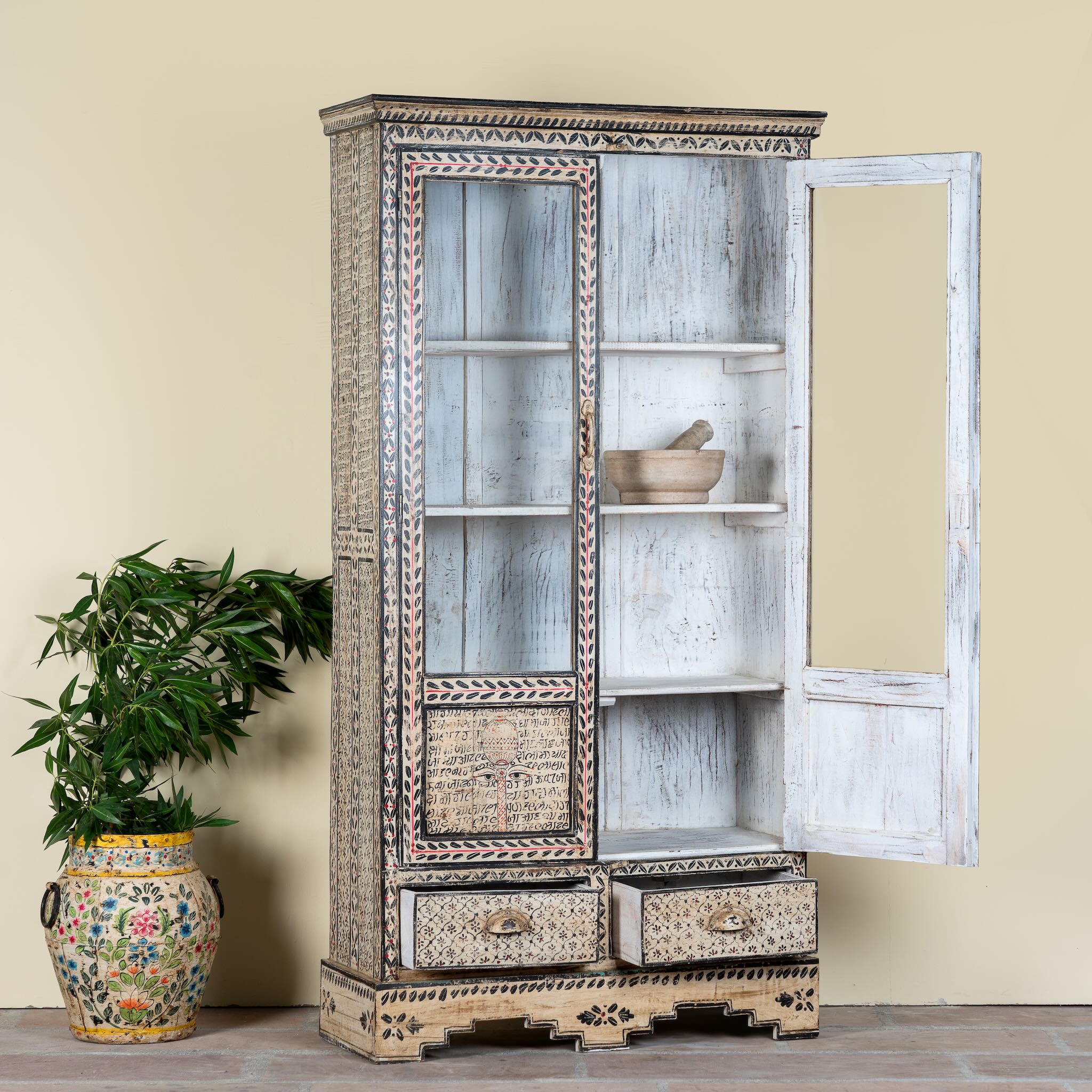 Decorative hand painted wooden cabinet Ritesh with open doors on a beige wall background.