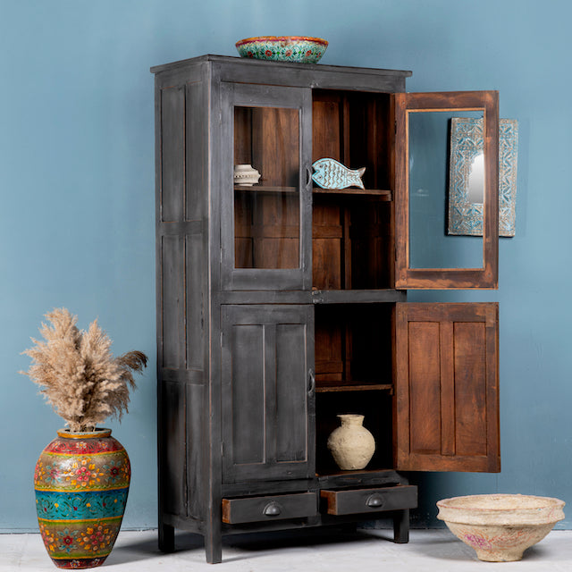 Side angle image with open doors of a shabby chic grey teak wood cabinet with glass doors and drawers – sustainable furniture for classic, rustic, or vintage interiors.