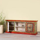 Side angle image showing open door of a hand-painted reclaimed wood vintage lowboard with floral motifs – a colourful piece of sustainable furniture for artistic and rustic interiors.