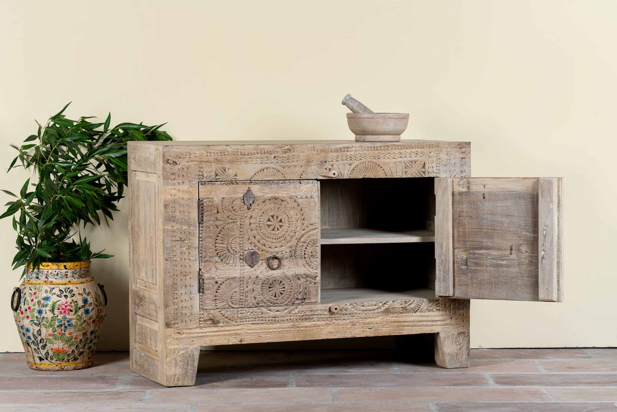Side angle image with open door of a sideboard Taksh made from reclaimed teak wood, featuring carved antique Indian door fronts with circular mandala motifs. A unique piece of old door furniture combining Mediterranean style with traditional Indian craftsmanship.