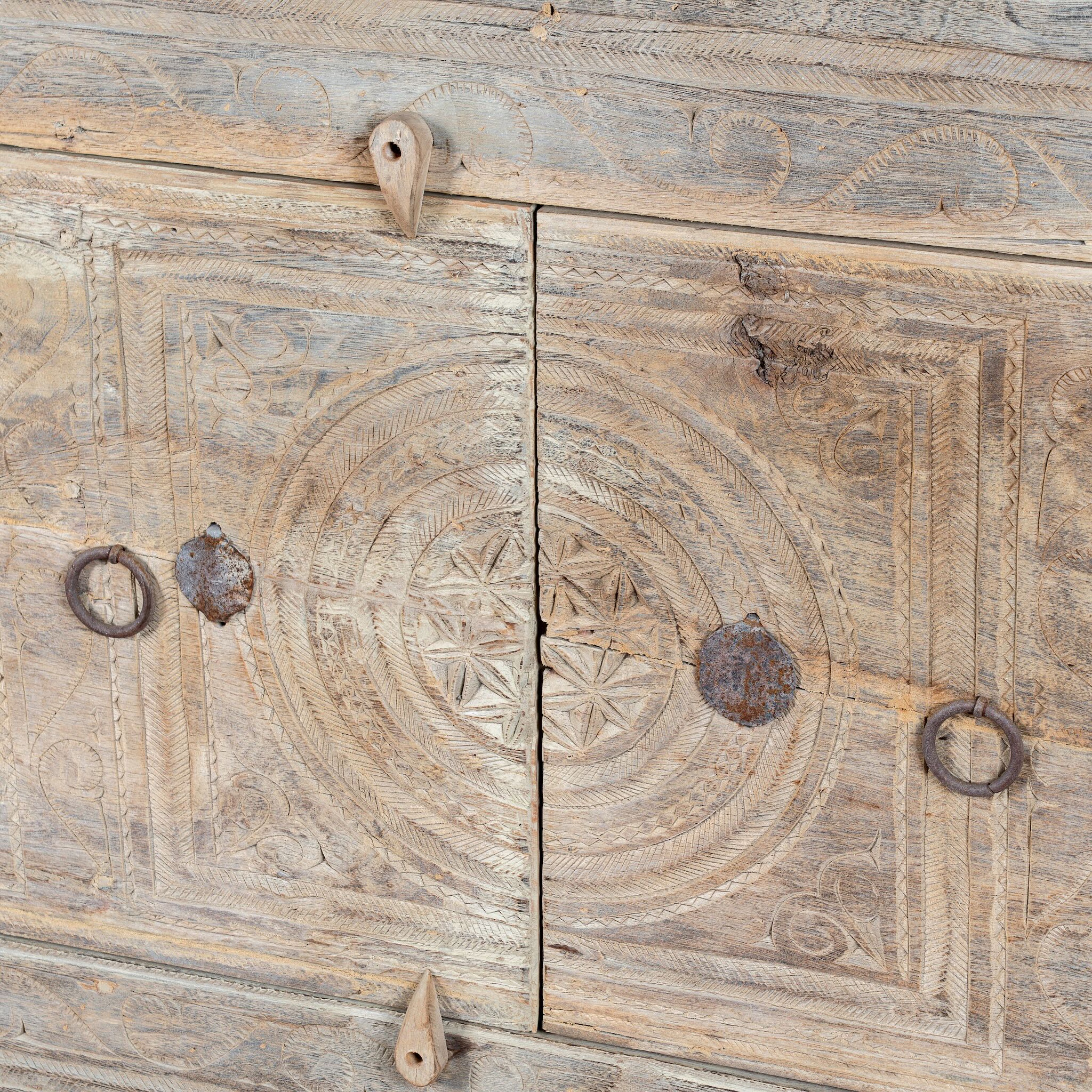 Close up image of a handcrafted sideboard Tanay made from reclaimed teak wood, featuring antique Indian door fronts with original carvings. A Mediterranean-inspired piece of unique Indian furniture with sustainable character and functional storage.