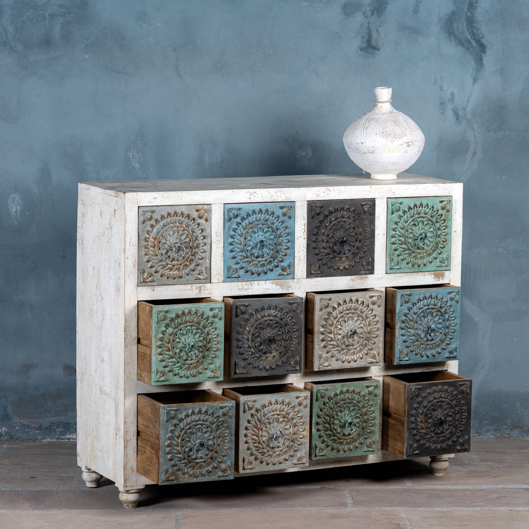 Wooden dresser with decorative embossed panels against a gray wall