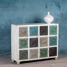 Side angle view of a chest of 12 drawers made from mango wood, featuring hand-carved floral fronts in a mix of turquoise, black, and natural tones- a vibrant statement piece with vintage charm.