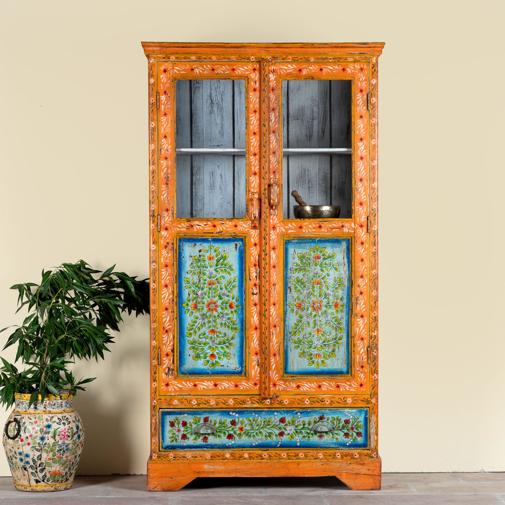 Lifestyle image of a hand painted reclaimed wood showcase with 2 doors and one drawer.