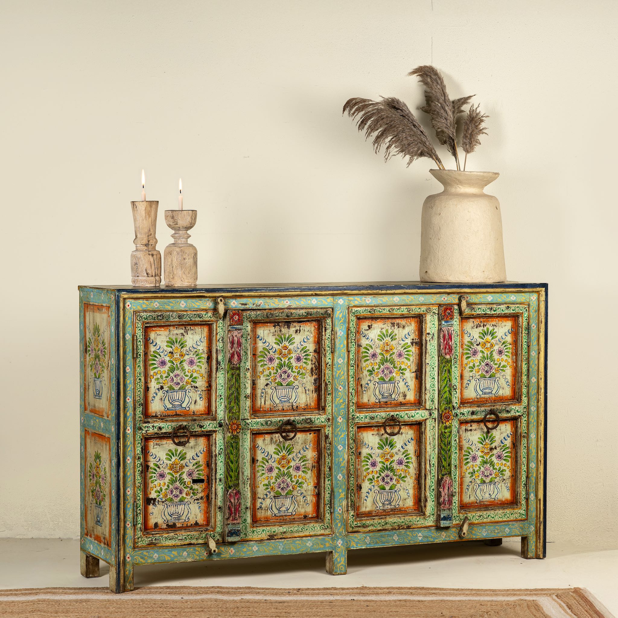 Side angle image of a reclaimed wood sideboard with hand painted floral motifs and distressed finish; artisanal storage furniture for bohemian interiors, 170 × 40 × 104 cm.