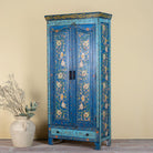 Side angle image with closed doors o a hand-painted wardrobe made of reclaimed wood in vibrant blue floral design – Yuvika model by Om Home & Garden