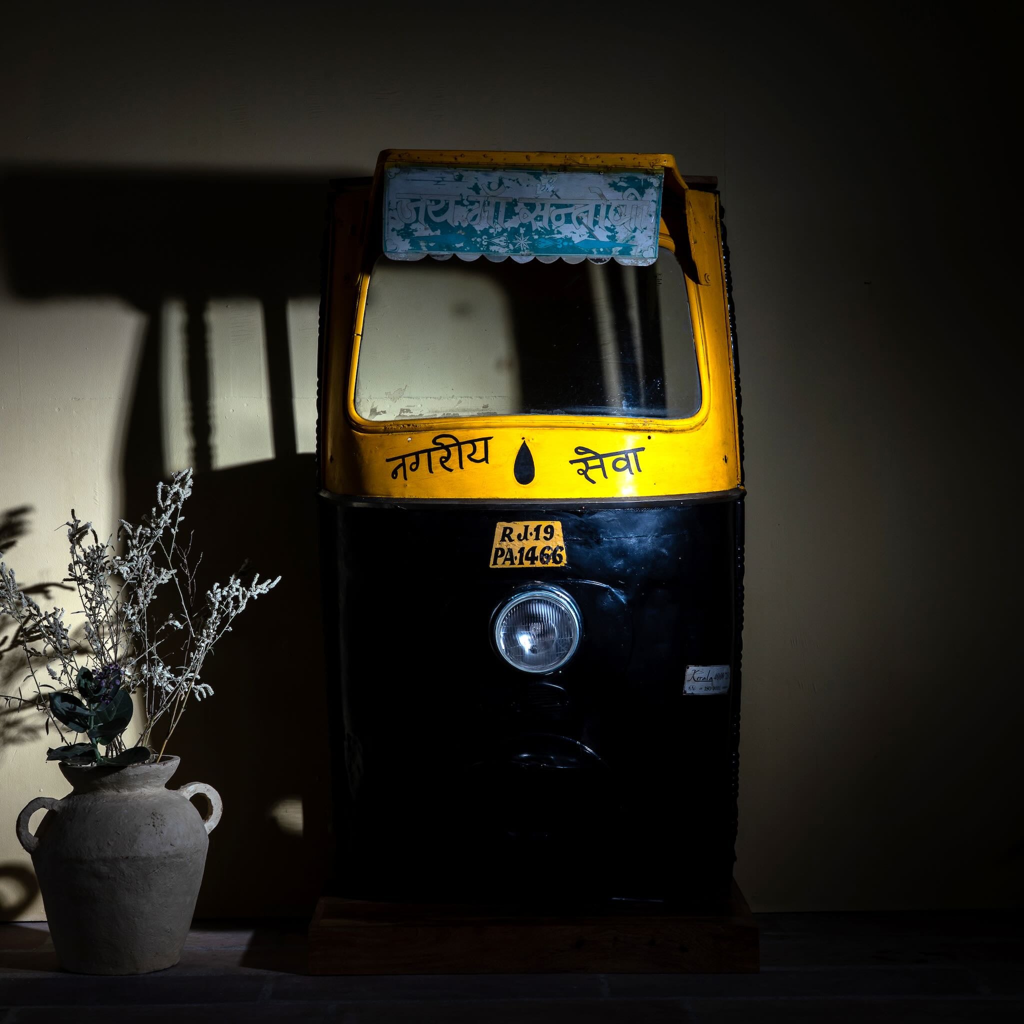 Lifestyle image of a artsy bar table made from a reclaimed Indian rickshaw front with working headlight – Zoha Riksha bar model by Om Home & Garden