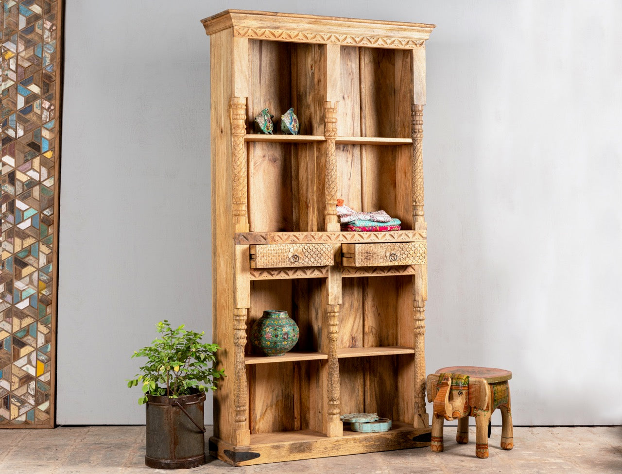 Side angle image with open drawers of a handcrafted mango wood bookshelf with carved detailing – mango wood shelving and carved wooden furniture in a warm brown finish for timeless interiors.