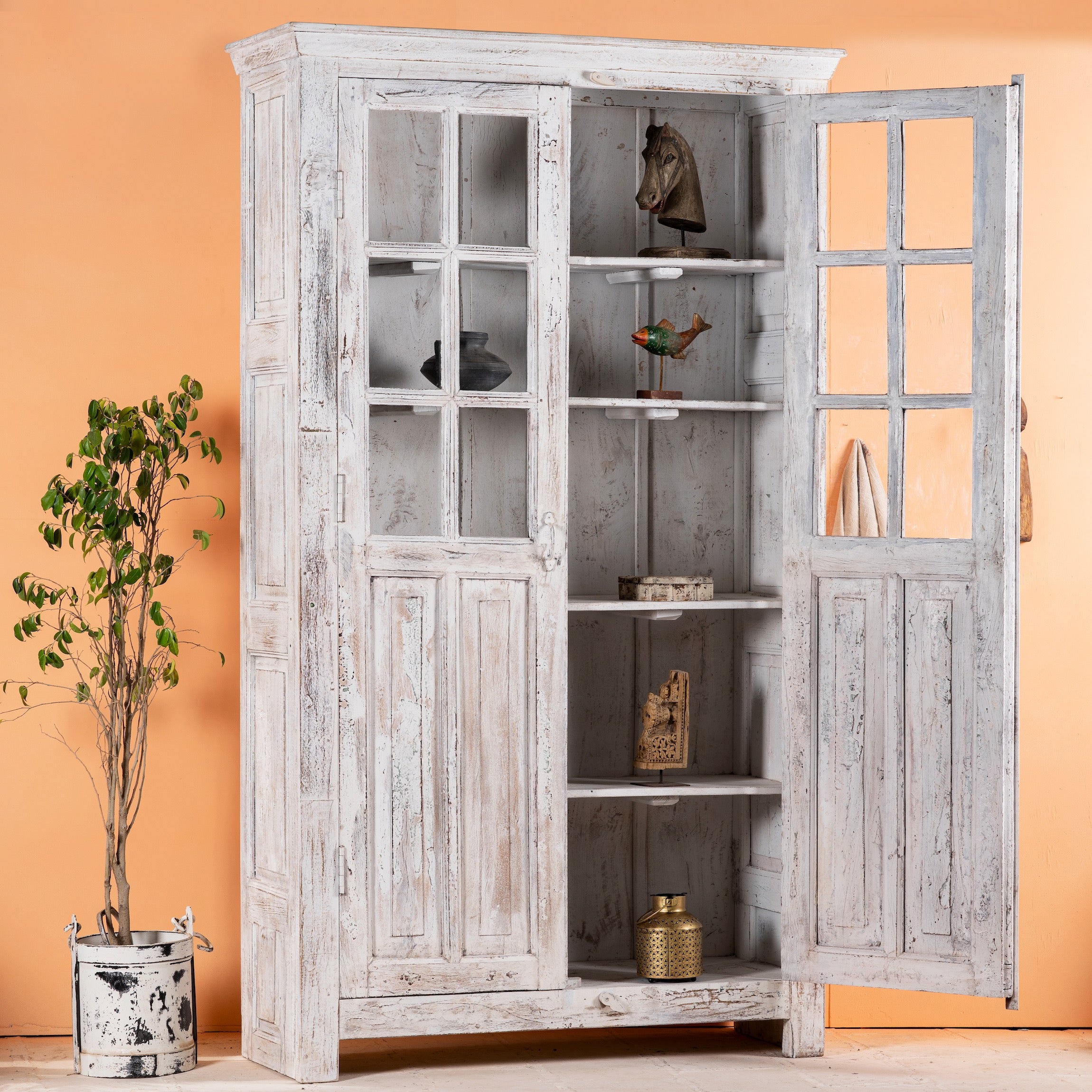 Side angle image with open door of a refurbished antique teak wood display cabinet with whitewashed finish and glass doors – wooden display cabinet blending Mediterranean charm and timeless craftsmanship.