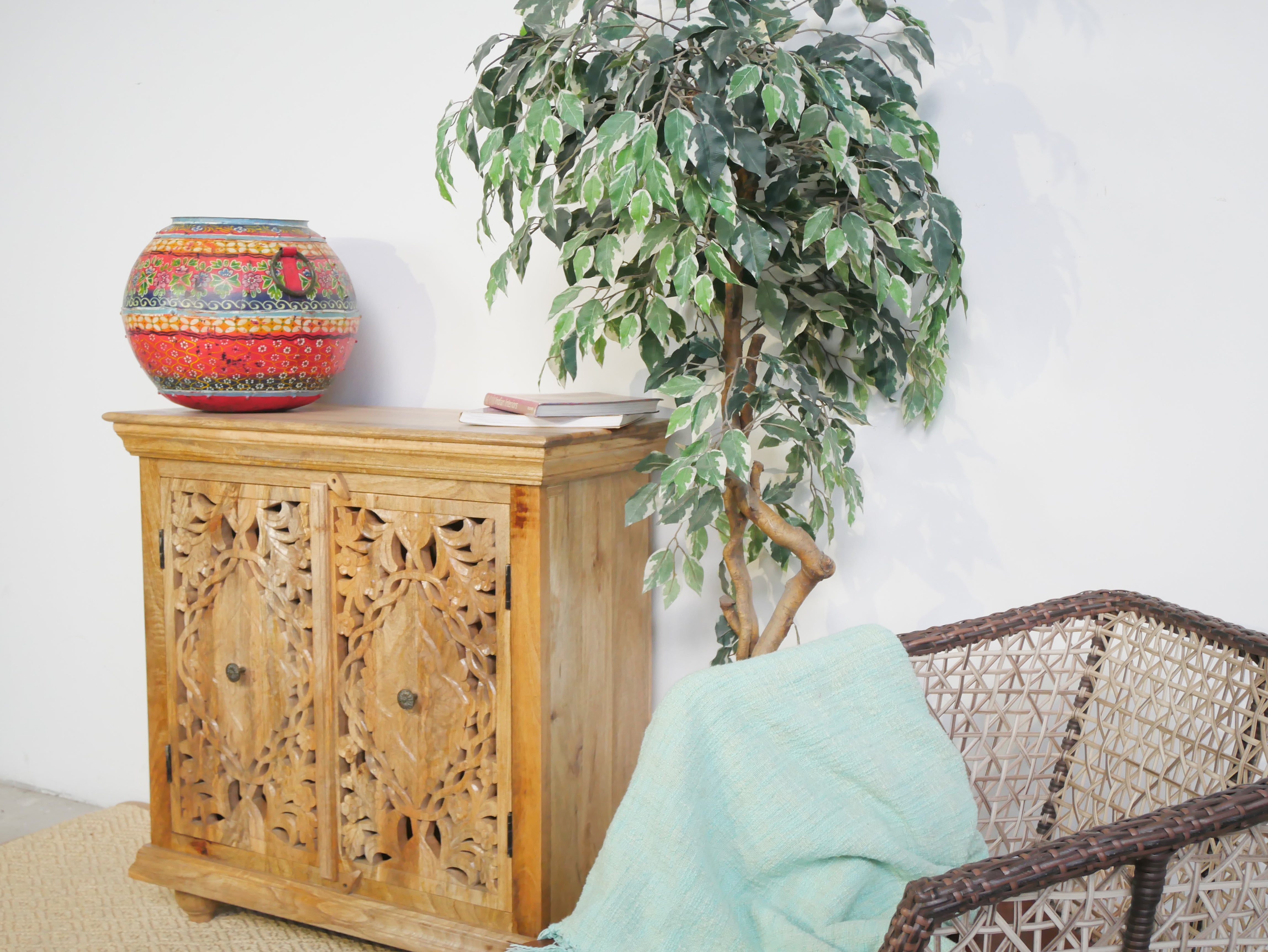 Side angle image of a carved wood furniture cupboard in solid mango wood with handmade floral carvings, Mediterranean-style, 90 × 90 × 40 cm.
